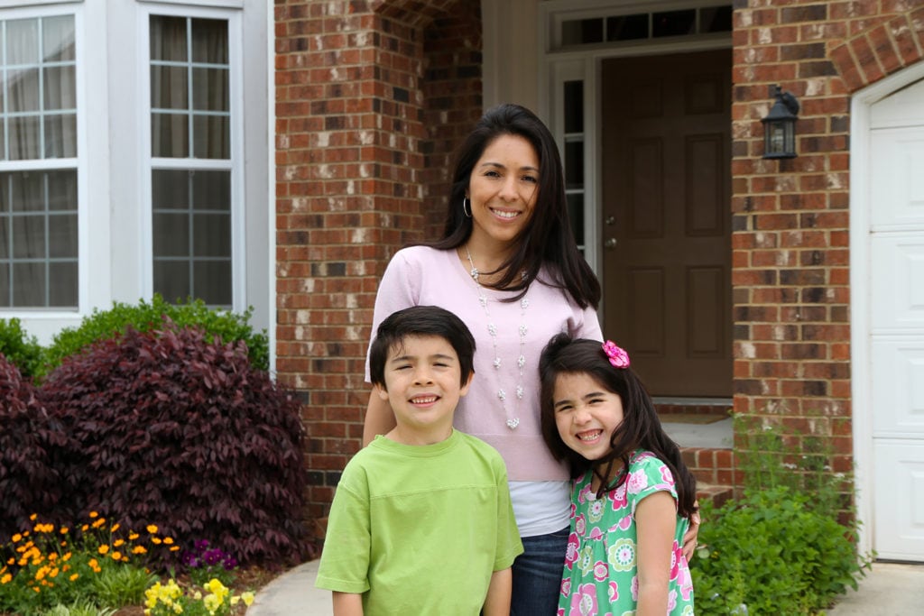 family standing outside their home in summer